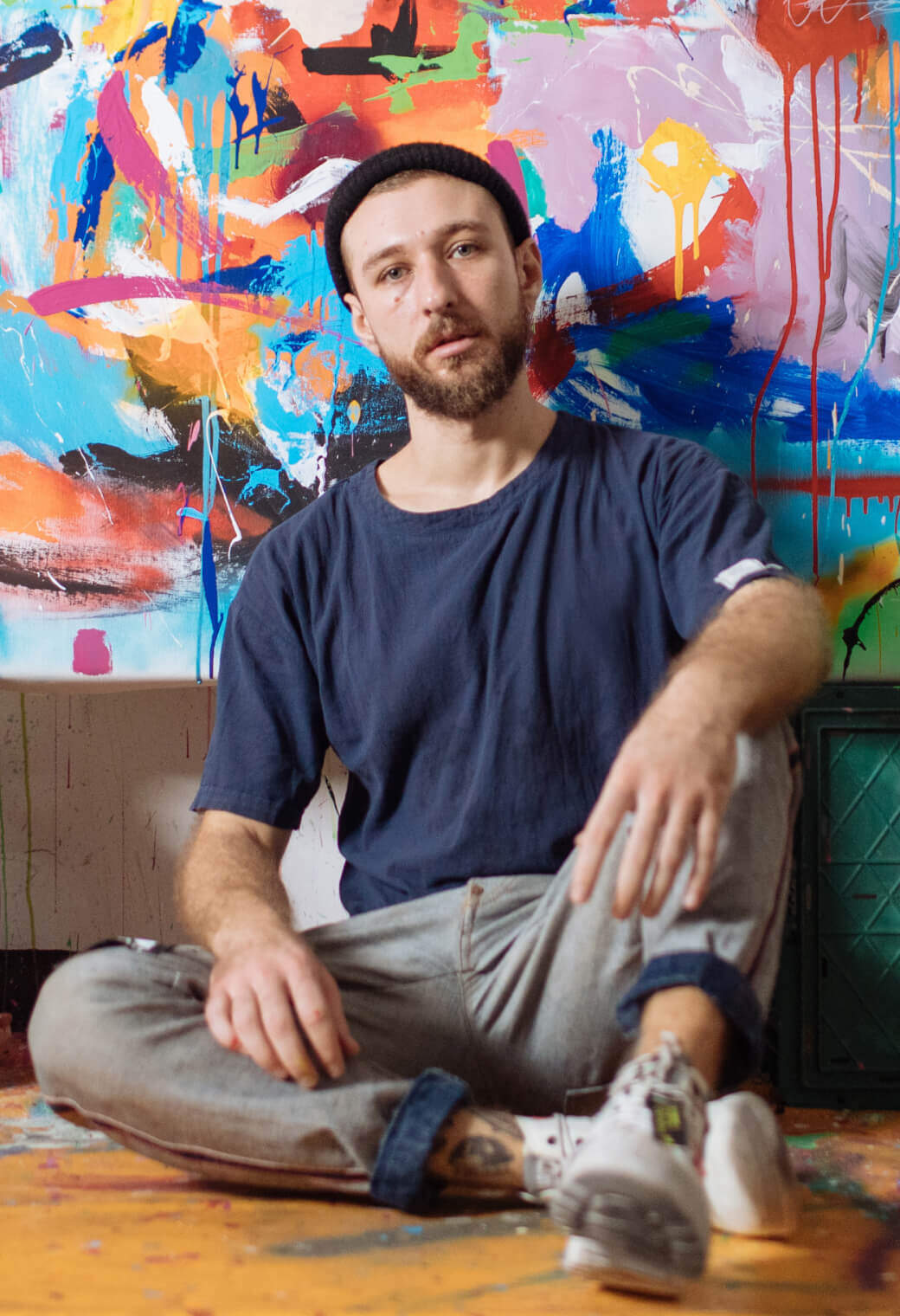 Person sitting agains a colorful painting on a wall