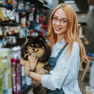 Small business owner of a pet store holding her dog 