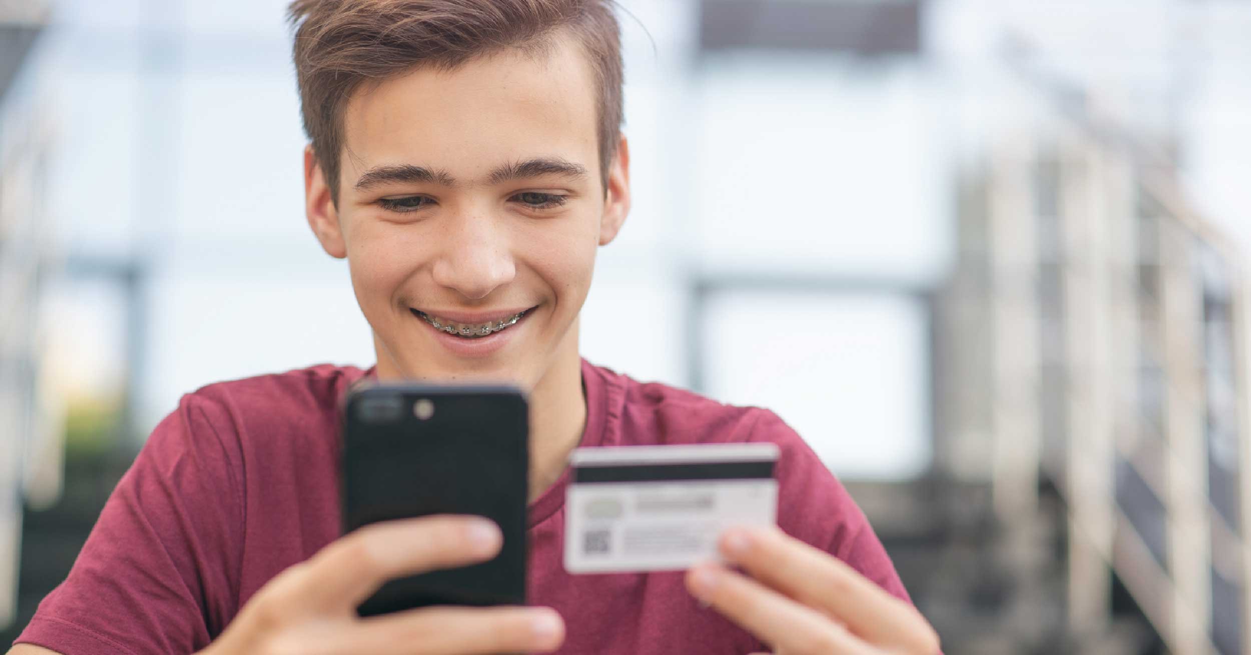 Teen using debit card on his phone
