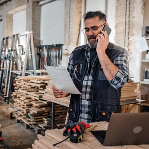 Business owner looking at his finances, standing on the phone