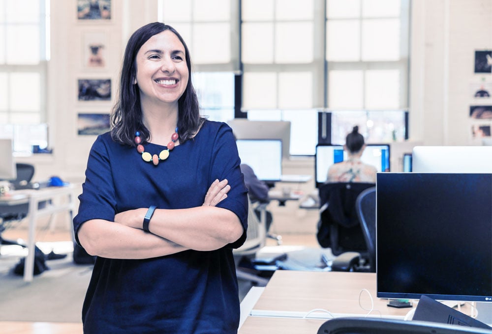 Business owner standing with her arms crossed in front of a room with computers