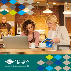 Business owner and baker talking at counter with laptop