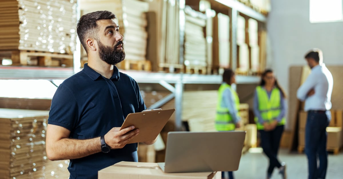 Business owner standing in his warehouse with clipboard