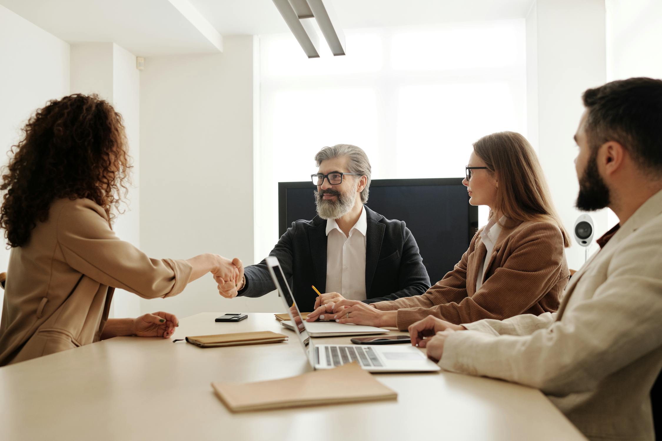 Woman and man shaking hand with another woman next to them
