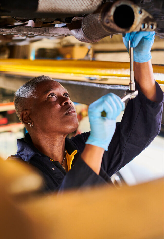 Person working on the under side of a car with tools