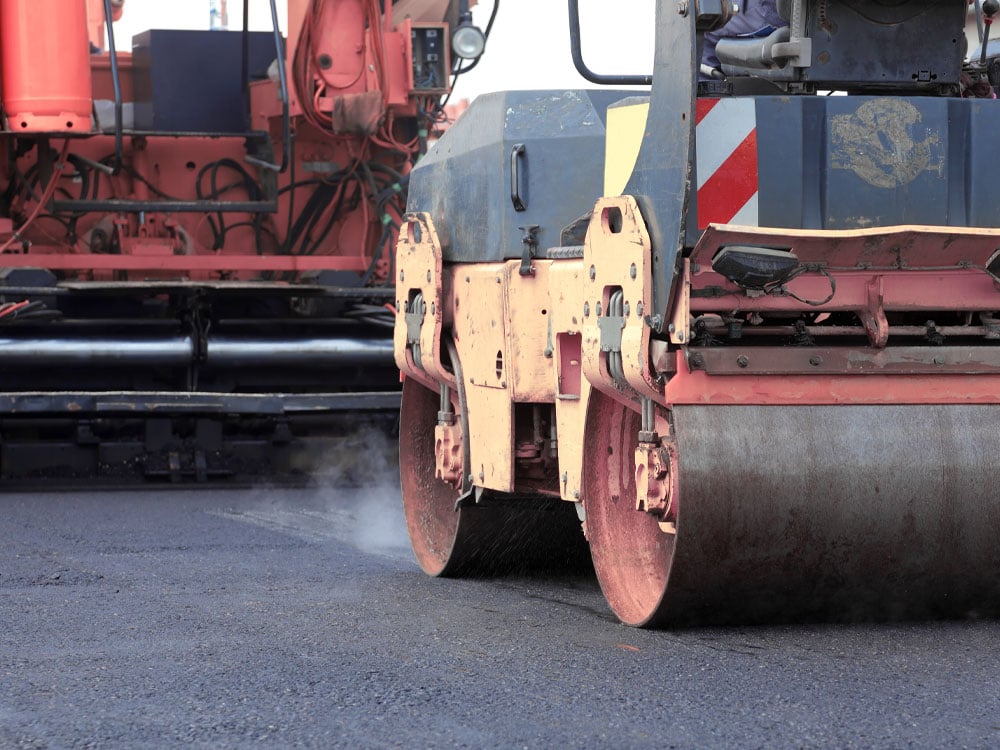 Steam roller heavy equipment flattening asphalt