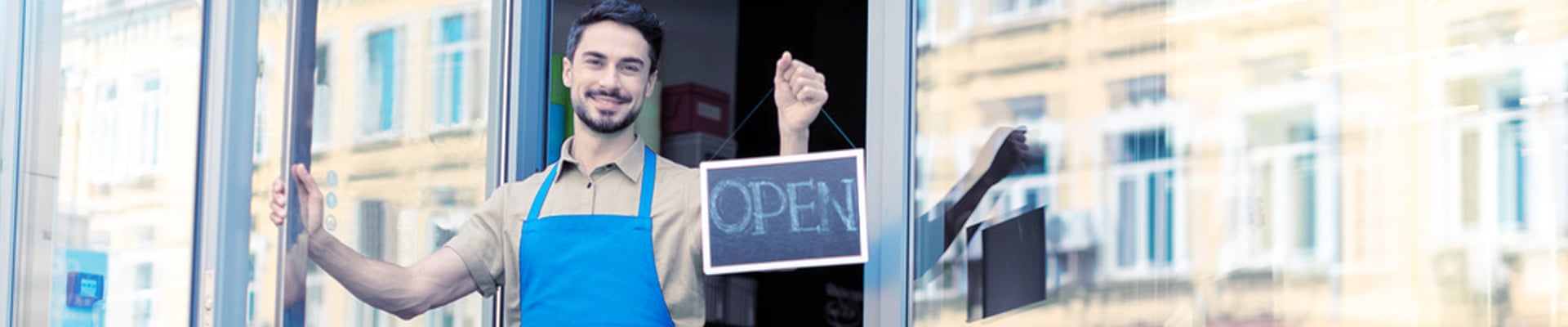 Business owner in doorway, holding the door and open sign